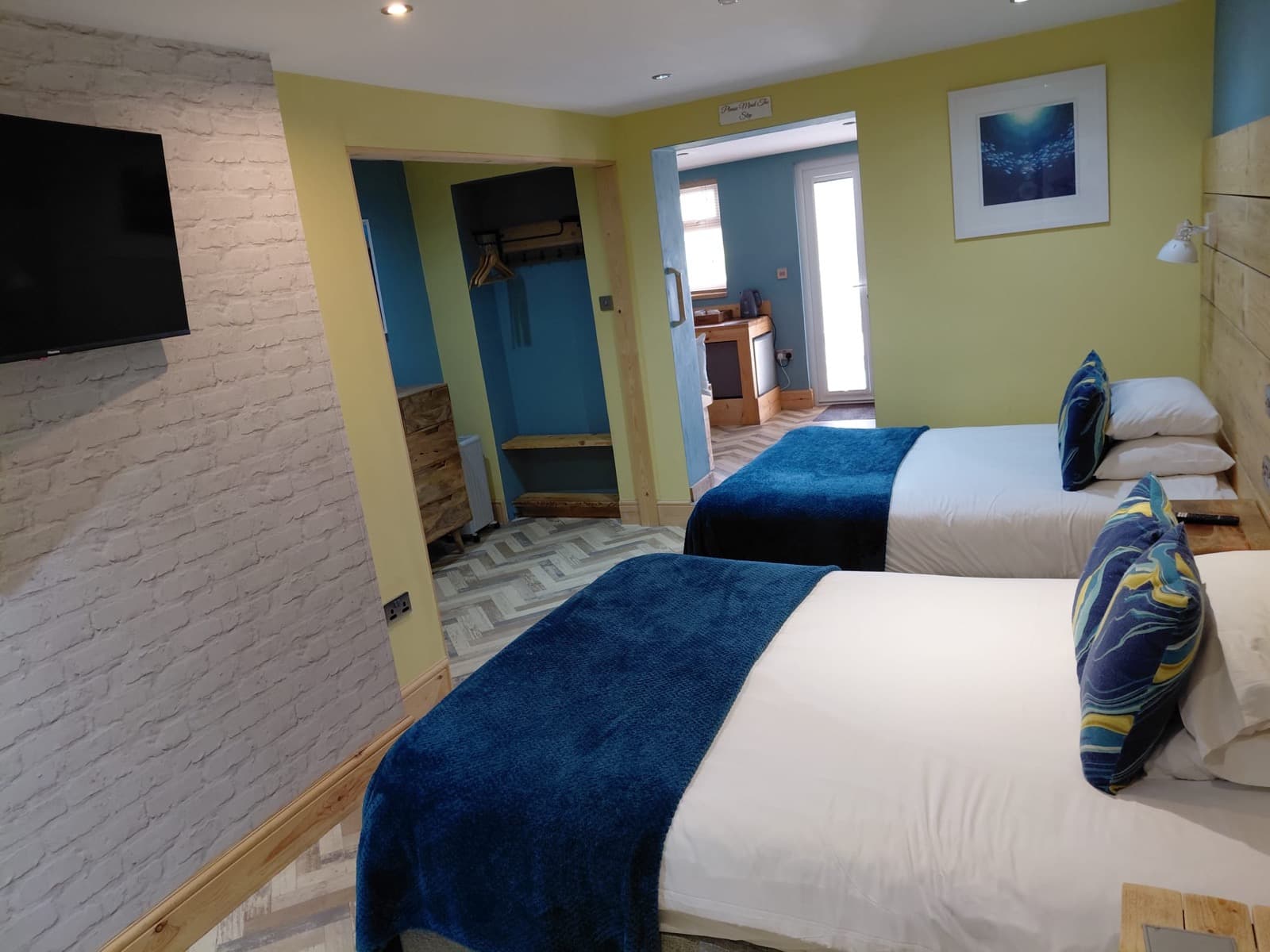 A ground-floor twin room at Seals Bacton with blue throws and coastal decor