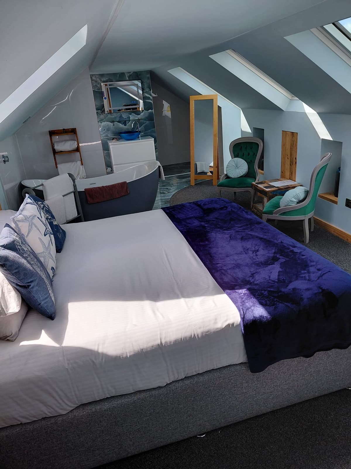 A loft-style double room at Seals Bacton with purple bedding