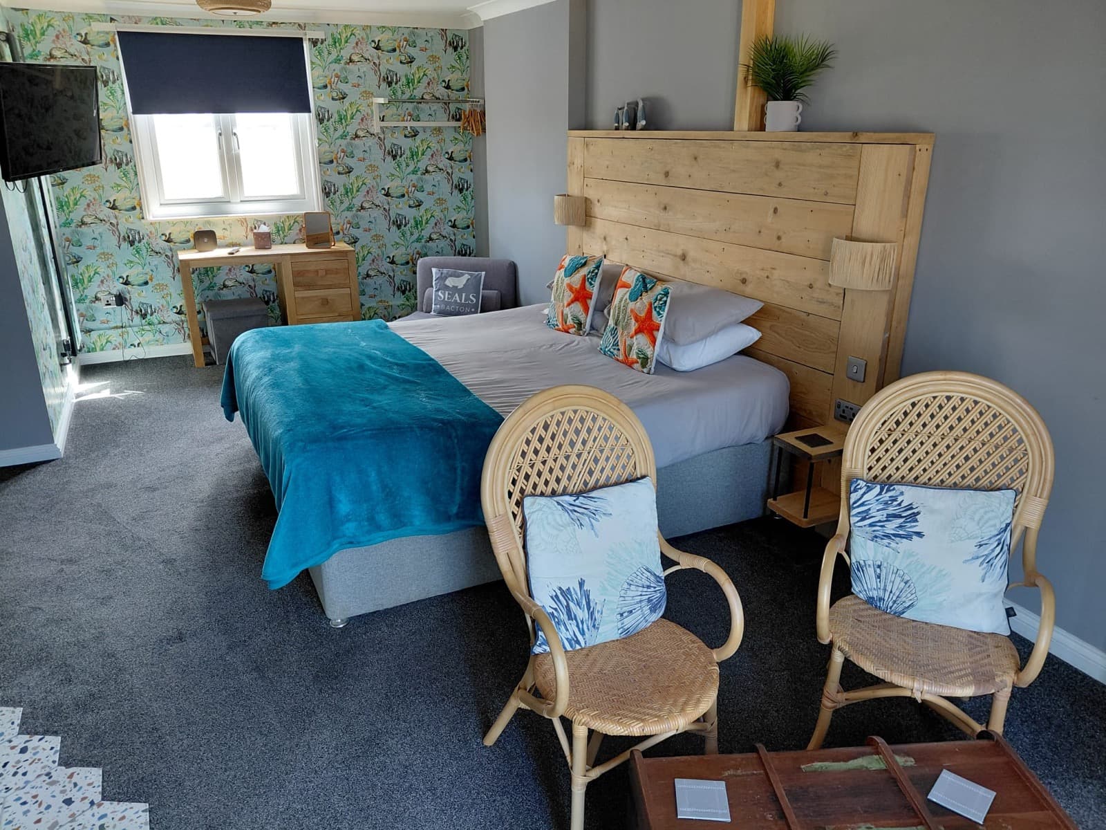 A blue-accented room at Seals Bacton with seating and a bathroom beyond