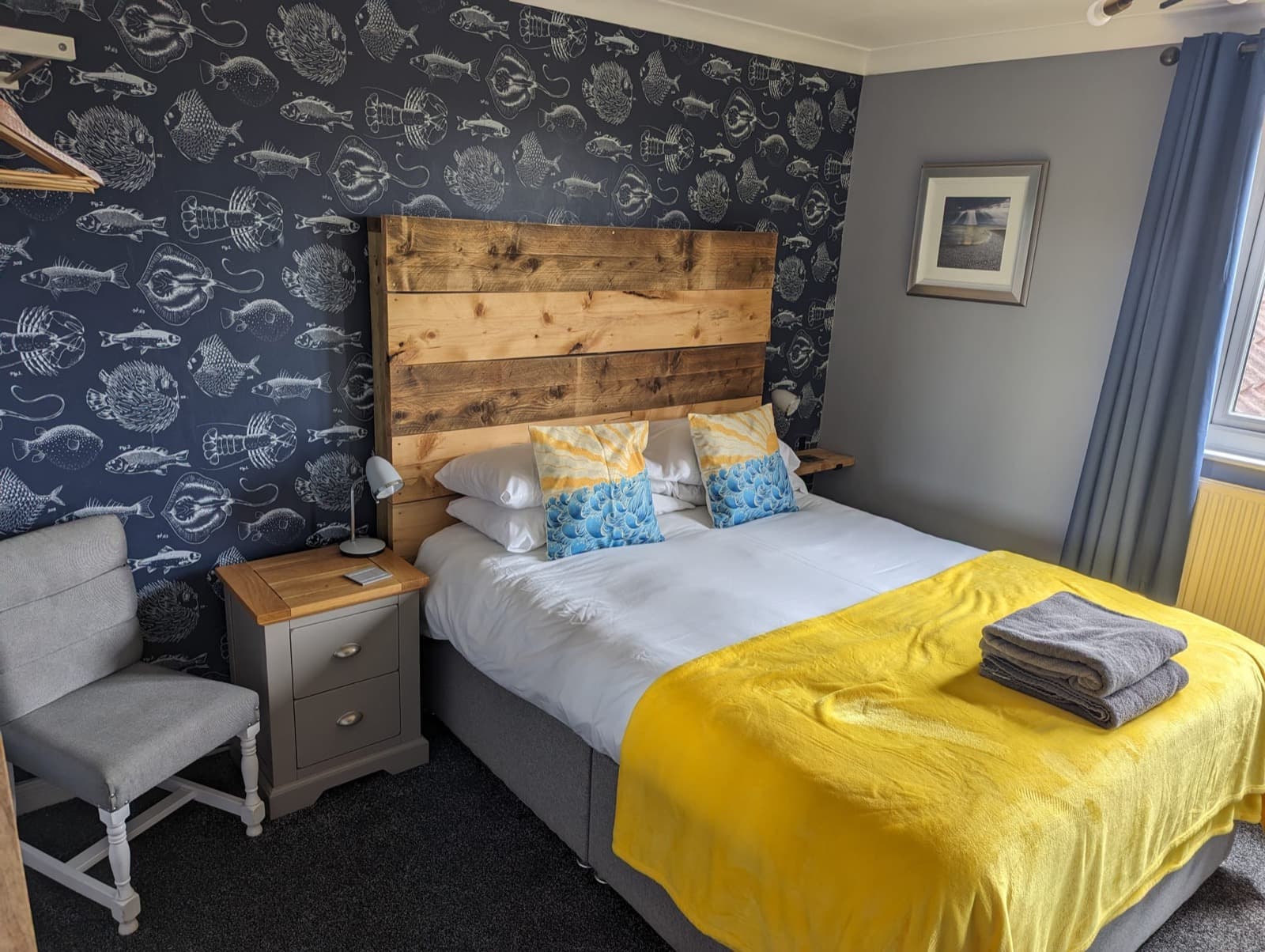 A double room at Seals Bacton with a yellow throw and patterned wall